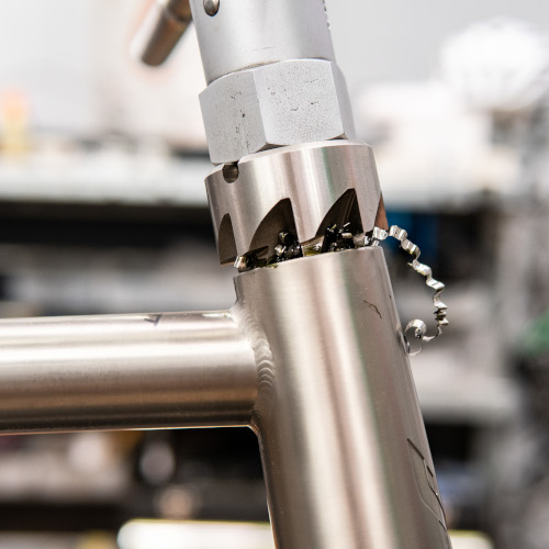 Pete, head mechanic at Bio-Mechanics Cycles & Repairs, sticking his finger in the seat tube of a bicycle frame.