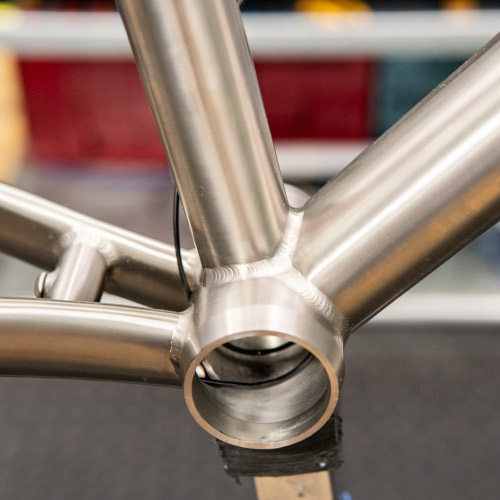 Close-up of the bottom bracket shell on a titanium bicycle frame, at Bio-Mechanics Cycles & Repairs in South Australia.