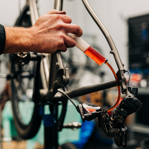 A professional bicycle mechanic bleeding a hydraulic brake (close up on his hand) at Bio-Mechanics Cycles & Repairs in South Australia.