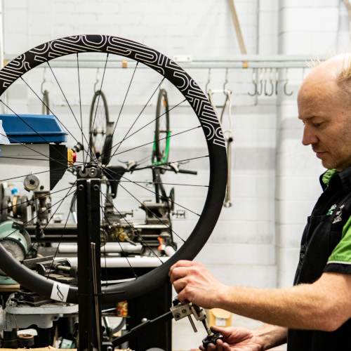 A professional bicycle mechanic truing a wheel at Bio-Mechanics Cycles & Repairs in South Australia.