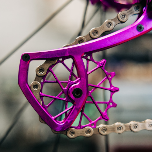 Close-up of a purple jockey wheel installed on a rear derailleur on a bicycle.