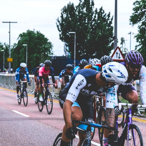 A pack of road cyclists, one in front looking back to the next one in line.