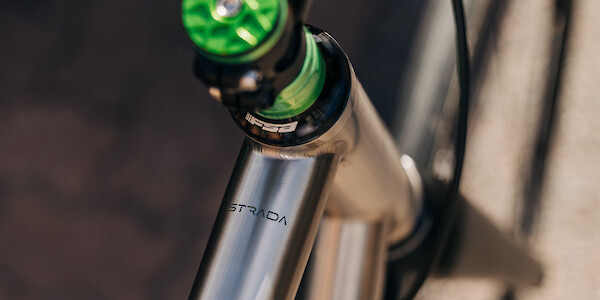 Top-tube decal detail on a Bossi Strada Classic titanium road bike, custom-built by Bio-Mechanics Cycles & Repairs, with green headset spacers and a green Garbaruk top cap.