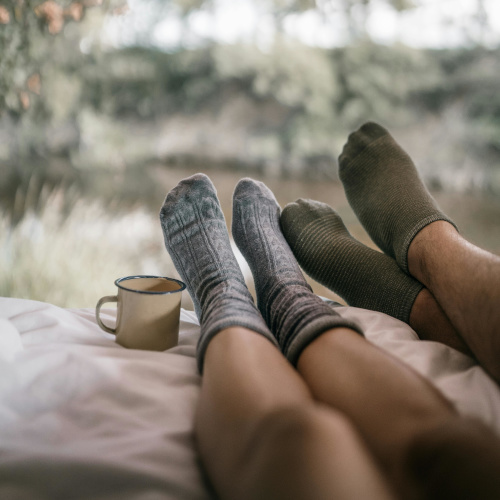 Two people's legs on a camping bed, wearing cosy socks.