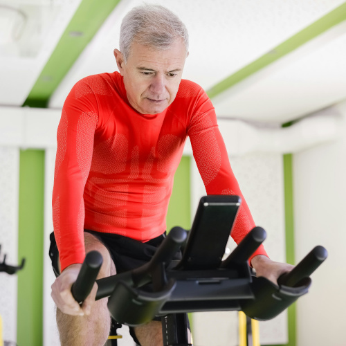 An older man on a stationary bicycle, looking at the screen.