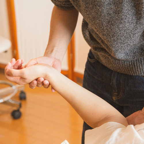 A physiotherapist manipulating a patient's arm. Neither of their faces is visible.