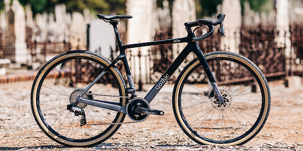 Gothic Cycles Aix carbon gravel bicycle, created by Bio-Mechanics Cycles & Repairs, shot in daylight in a graveyard setting.