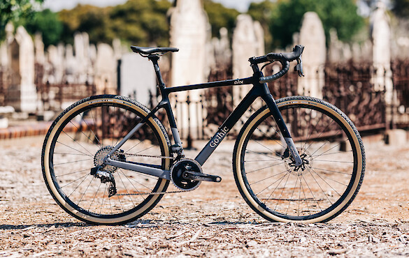 Gothic Cycles Aix carbon gravel bicycle, created by Bio-Mechanics Cycles & Repairs, shot in daylight in a graveyard setting.