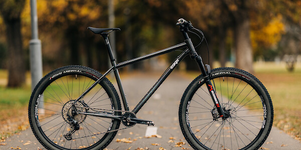 An Esker Hayduke touring mountain bike, custom-built by Bio-Mechanics Cycles & Repairs, shot on a footpath with a leafy autumnal background.