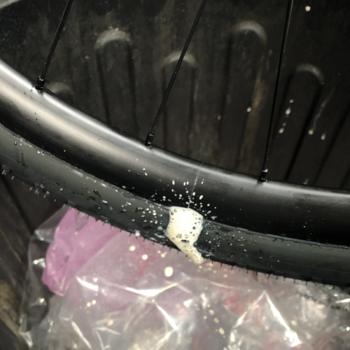 Tyre sealant bubbling out of a bicycle wheel, positioned over a bin.