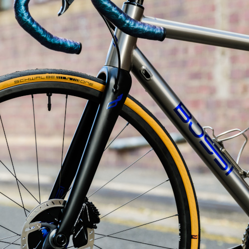 A titanium Bossi Summit endurance bicycle, custom-built by Bio-Mechanics Cycles & Repairs and photographed in an alleyway.