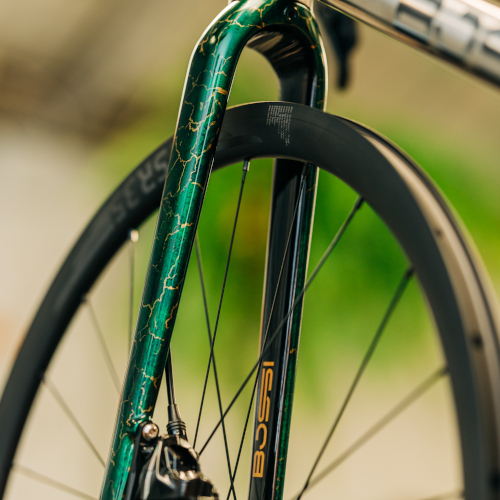 A marble-patterned gold and green Bossi bicycle fork, created at Bio-Mechanics Cycles & Repairs.