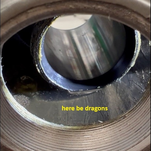 A close-up photograph of a bicycle frame bottom bracket shell, with water pooled inside it.