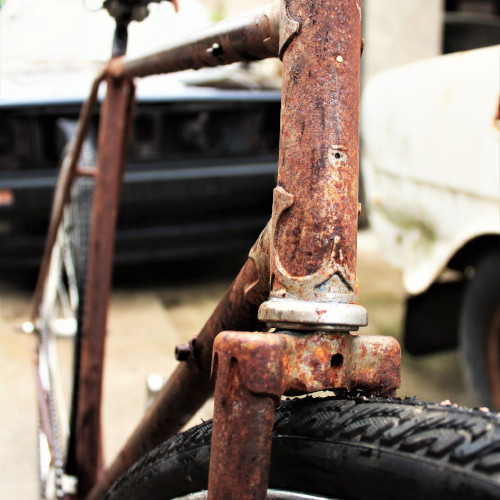 A bicycle frame riddled with rust.