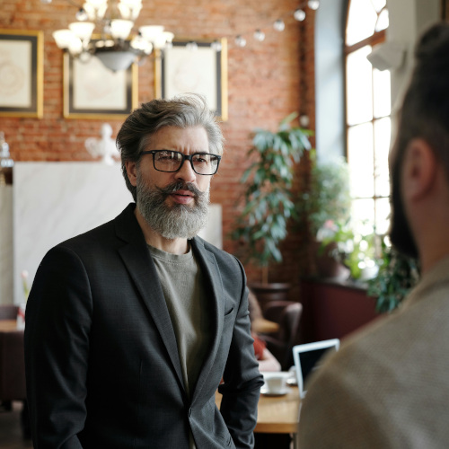 A bearded man, looking askance at another man as if he's just received some bad news.