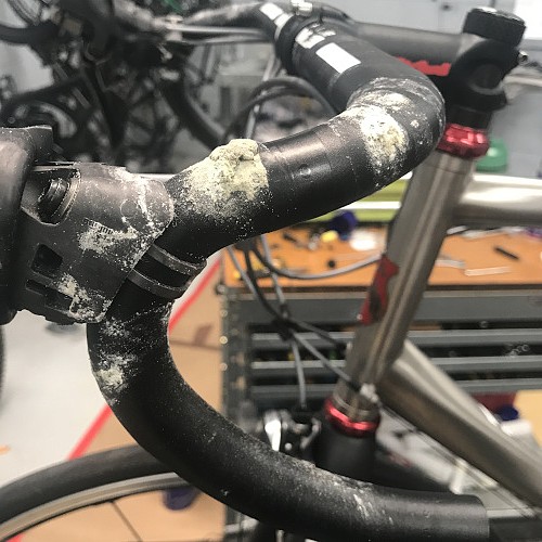 A bicycle handlebar covered in dried sweat (salt) that has eaten holes in it.