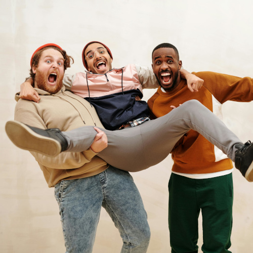 Three young men yelling excitedly, two of them holding up the third one between them. It's awkward.