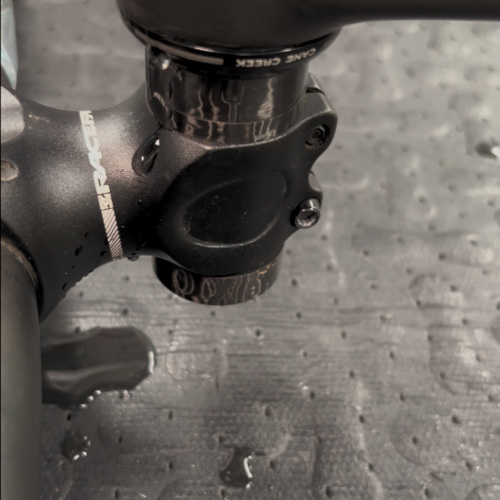 Close-up of a bicycle frame that's been tipped upside-down, water leaking out of the headset.