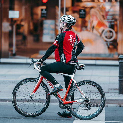 A gentleman on a road bike, standing at a set of traffic lights with an oddly upright posture.