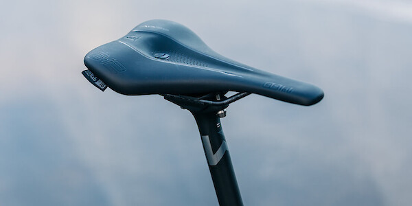 An SQLab 612 road saddle fitted to a Newmen carbon seat post, against a concrete background