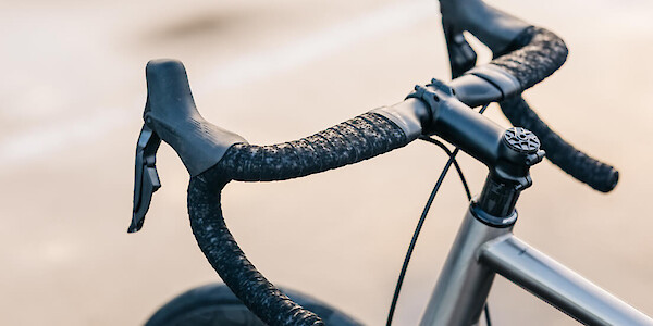 Carbon handlebar detail on a Bossi Summit titanium road bicycle, photographed outside in a carpark