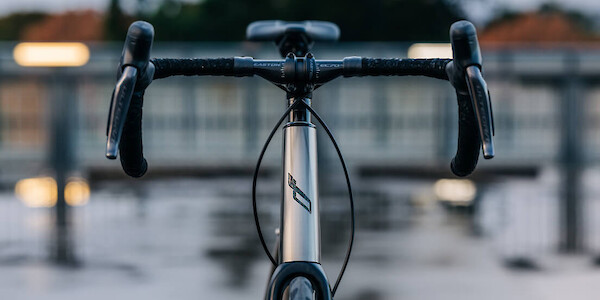 Front-on shot of a custom-built Bossi Summit titanium road bicycle, photographed on a roof carpark on a wet and moody day