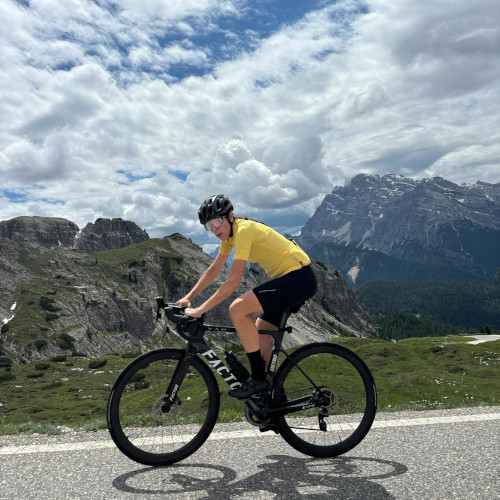 Woman riding a road bike in the hills, looking sideways at the camera and slightly annoyed.