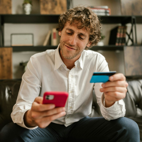 A man making a purchase on his phone, his credit card in hand.