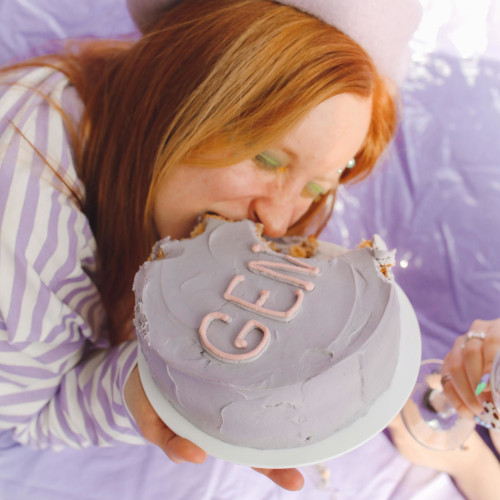 A woman stuffing a whole cake into her face.
