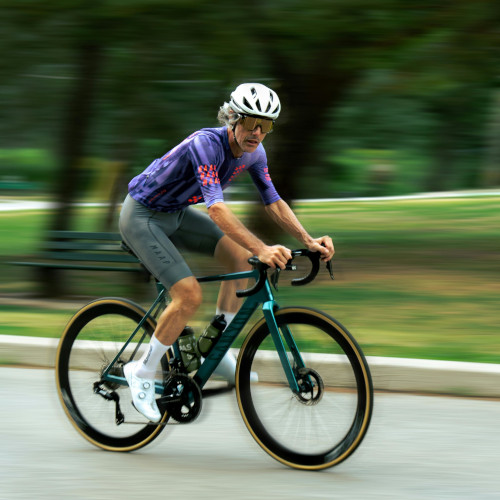 A road cyclist on a shiny green bike, looking strangely at the camera.