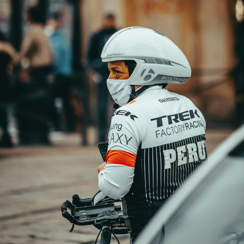 A cycling in traffic wearing bike gear, including a large aero-style helmet.