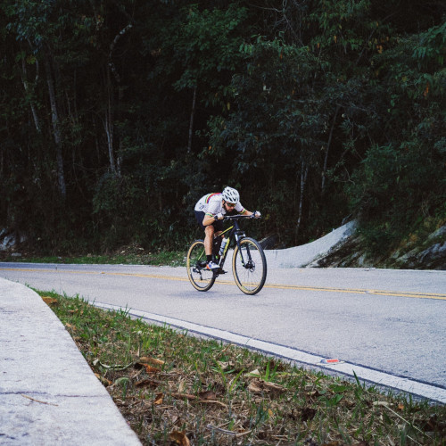 A mountain biker descending in a very flat aero position.