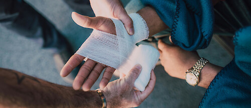 A person having their hands bandaged at the site of an accident.