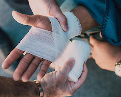 A person having their hands bandaged at the site of an accident.
