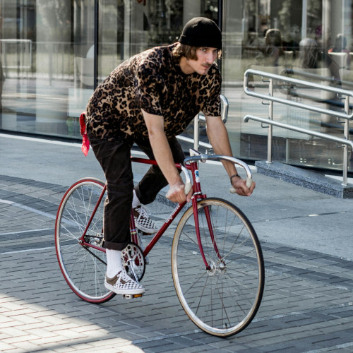 A young hipster riding a vintage drop-bar bike.