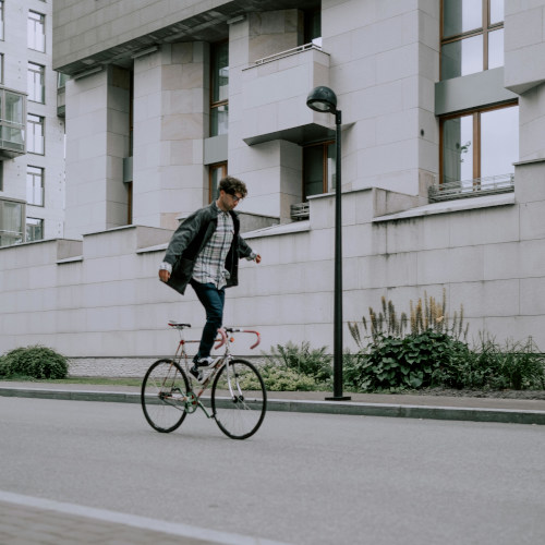 A young man doing a trick on his bike where he's riding it but standing on the frame.