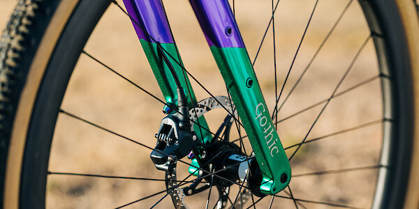 Fork and brake detail on a custom-built Gothic Aix carbon gravel bike in sparkle emerald green/purple