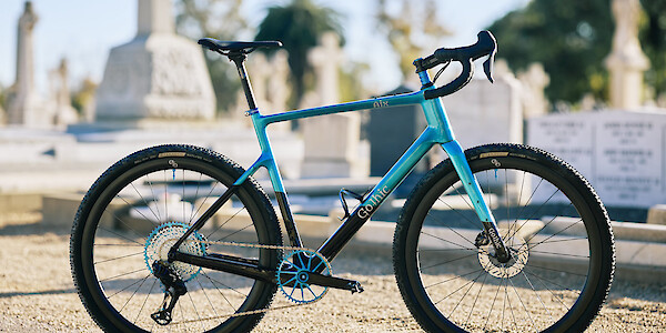 Custom-built carbon gravel bike by Gothic Cycles in a blue and black colour scheme, photographed in a graveyard