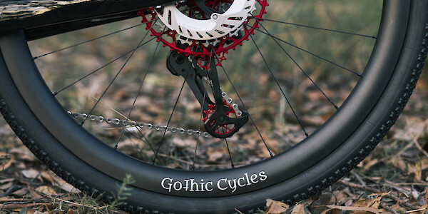Rear detail on red Garbaruk drivetrain components on a Gothic Cycles carbon gravel bike, photographed in a forest