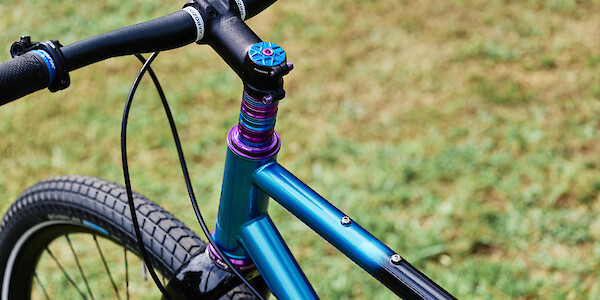 Blue Garbaruk top cap with purple titanium bolt, purple and blue Hope headset and spacers on a Veloci steel gravel bike